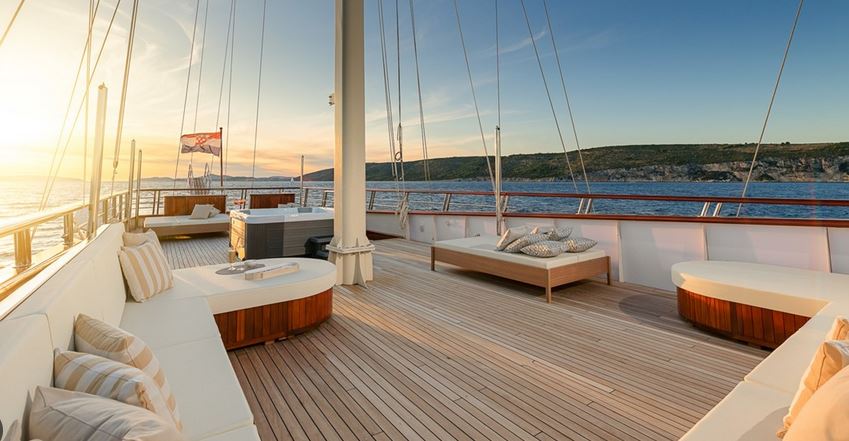 Die Besitzer eines Family Offices verfügen über eine Luxussegelyacht, deren Oberdeck mit Lounge-Bereich und Panoramablick auf das Meer, ausgestattet mit hochwertigen Holzdielen, einen idealen Ort für geselliges Beisammensein mit der Familie bietet.